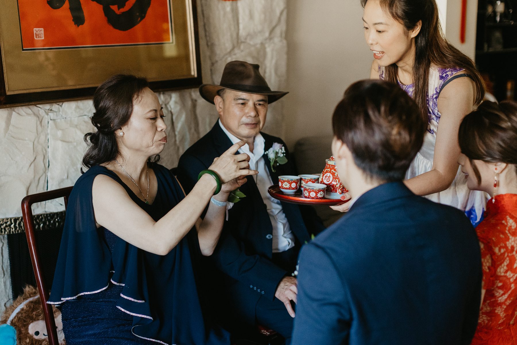 Bride in a red cheongsam laughing with her family during the morning tea ceremony