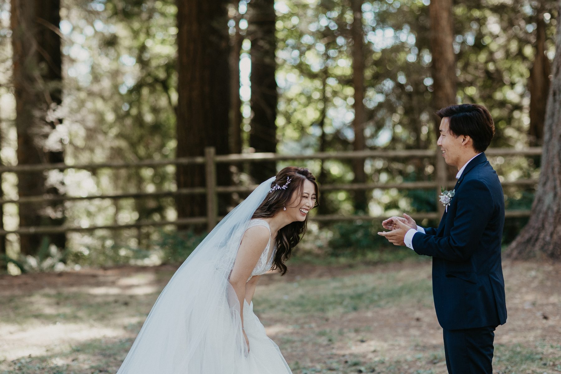 Bride turning to face her partner for the first look among tall evergreen trees