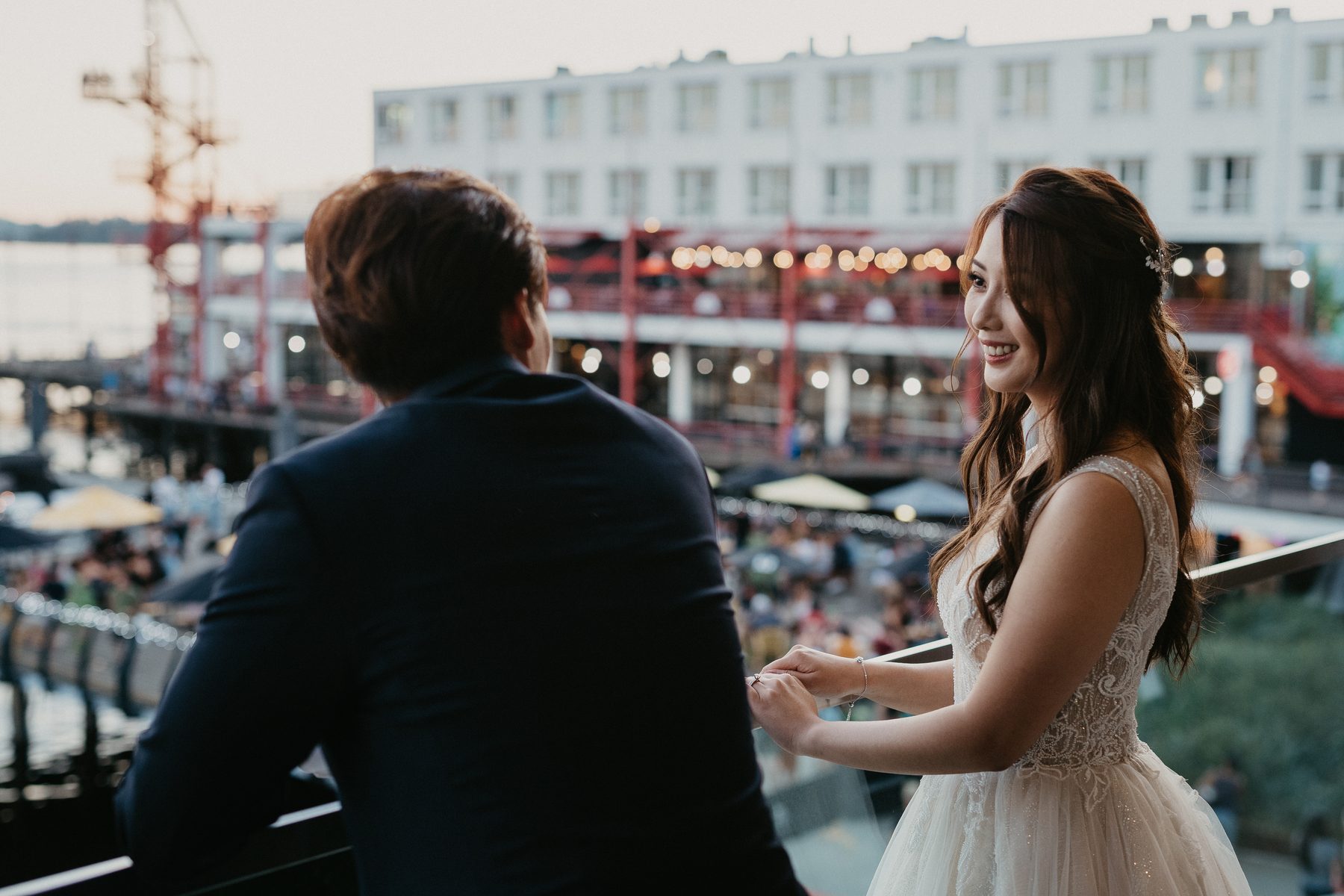 Christine and Hugh at golden hour on the North Vancouver waterfront with the pier and boats behind them