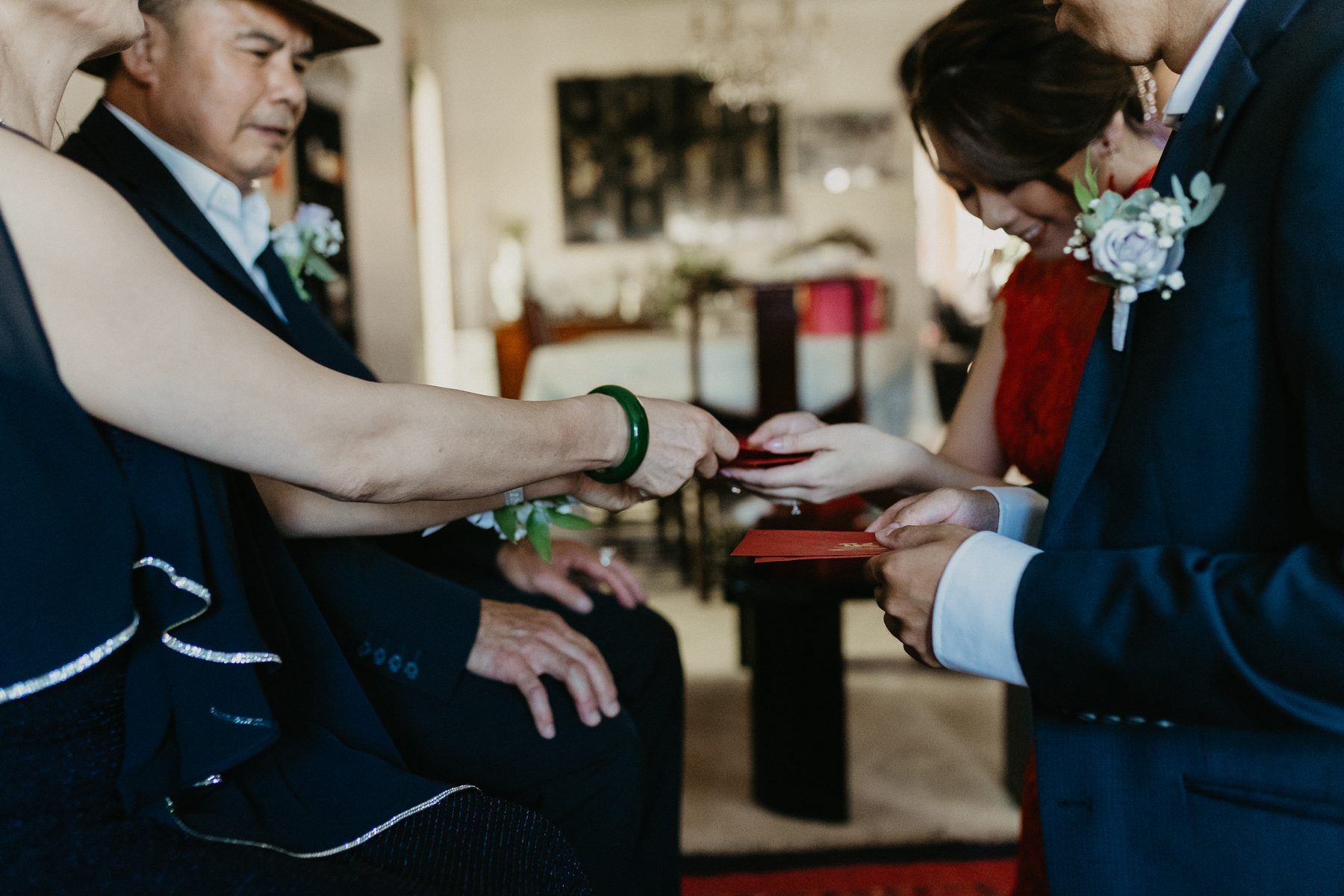 A red envelope passed from an elder's hand to the couple during the morning tea