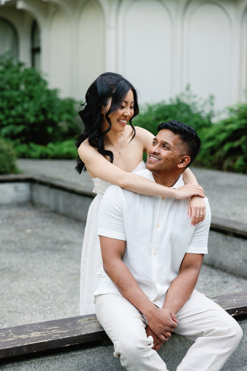 Ashan lifting Eunice, both laughing, against the white architecture near the Museum of Anthropology