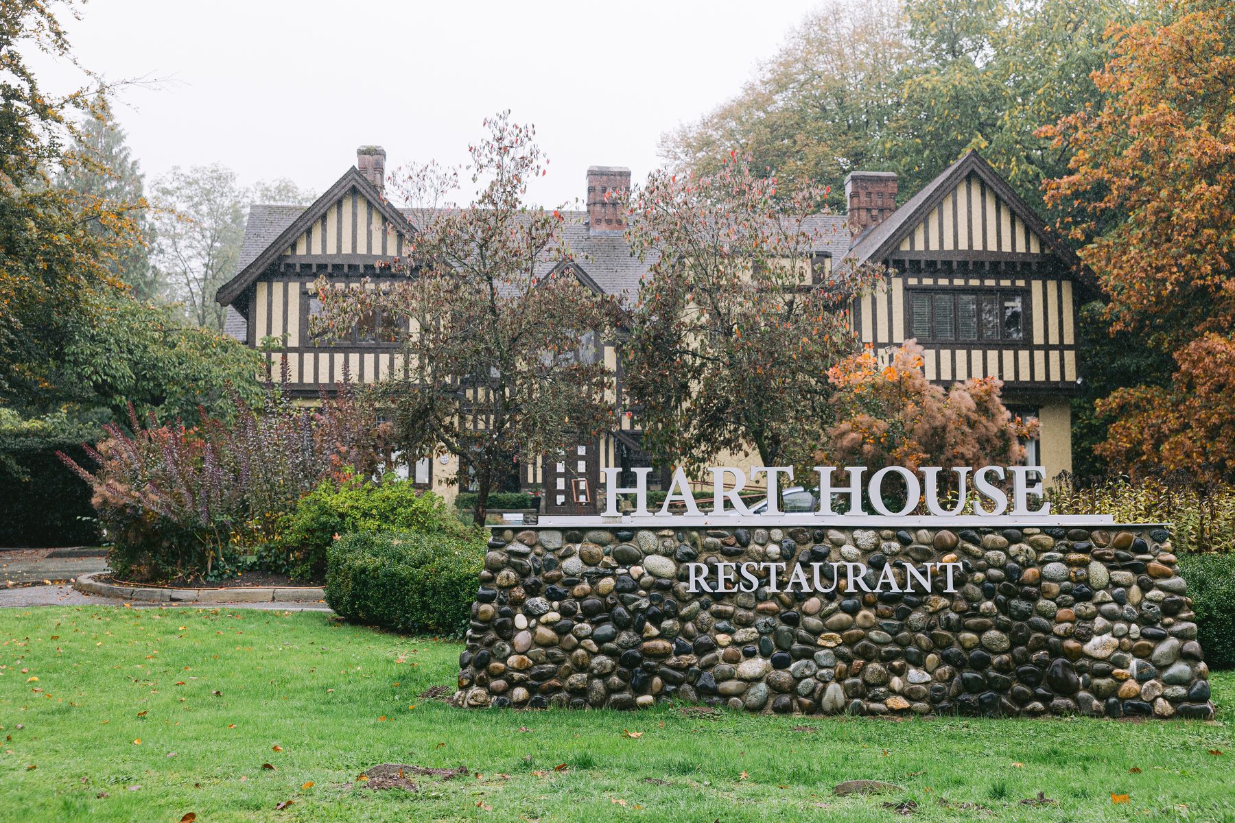 The Tudor Revival exterior of Hart House Restaurant seen from the lawn with the venue sign in the foreground