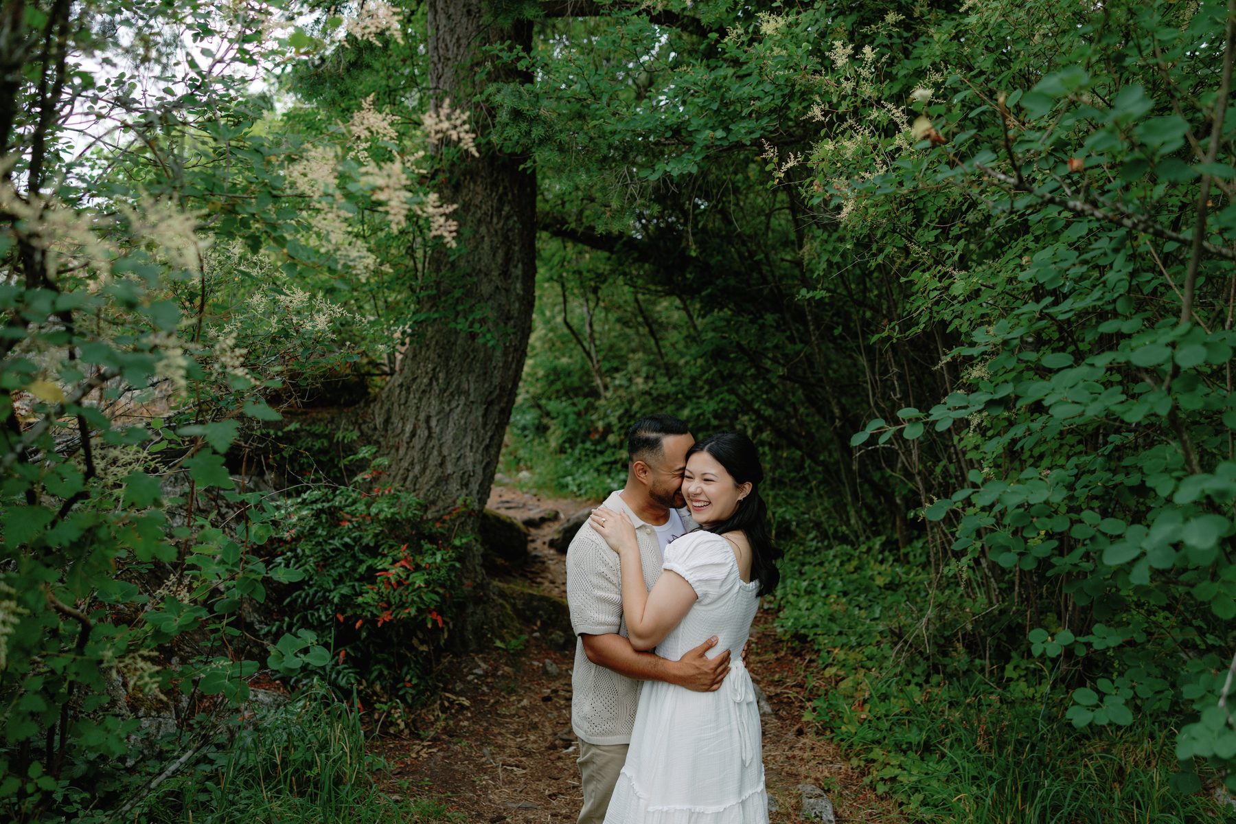 Couple embracing on a mossy trail in West Coast rainforest