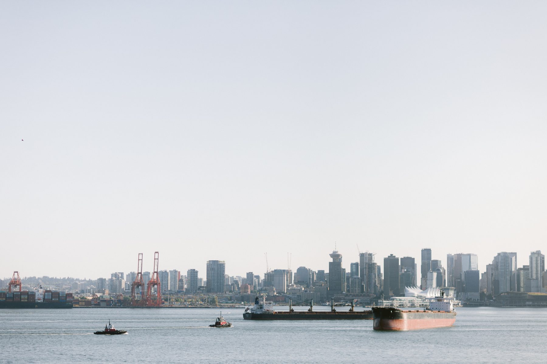 View across Burrard Inlet toward the downtown Vancouver skyline with a cargo ship passing in the channel
