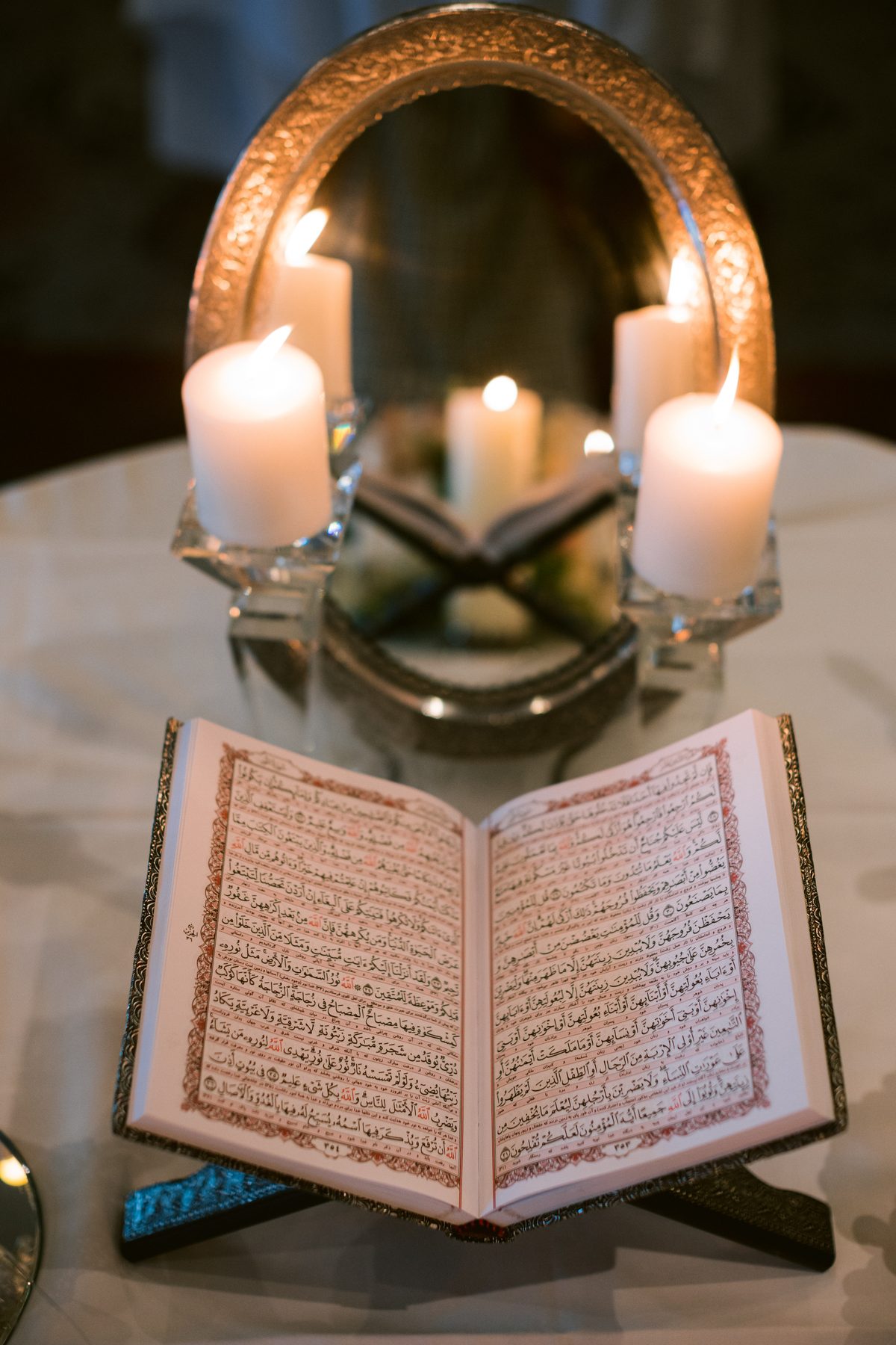An ornate mirror, lit candles and an open book arranged on the ceremony table before guests arrive