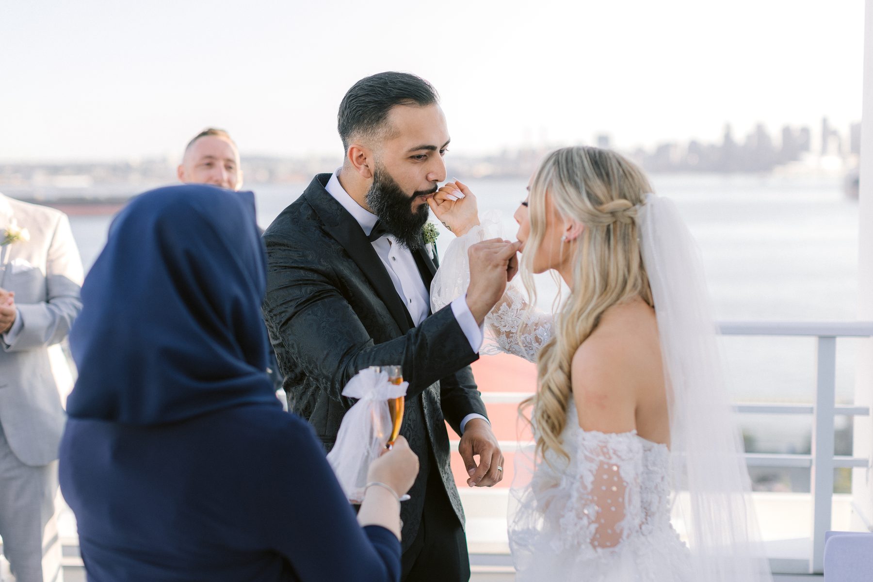 A guest holding the newly married couple in a long embrace on the rooftop after the ceremony