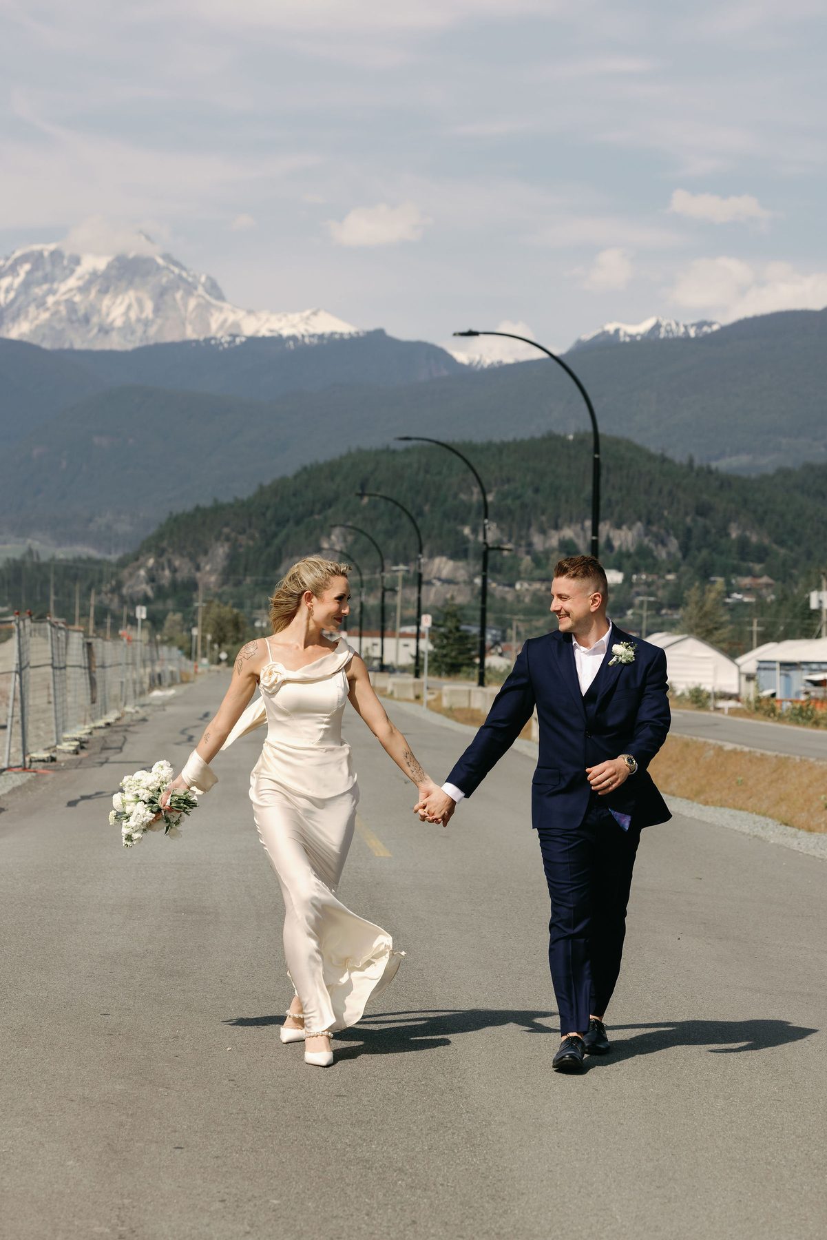 Couple walking a quiet road with snow-capped peaks in the distance