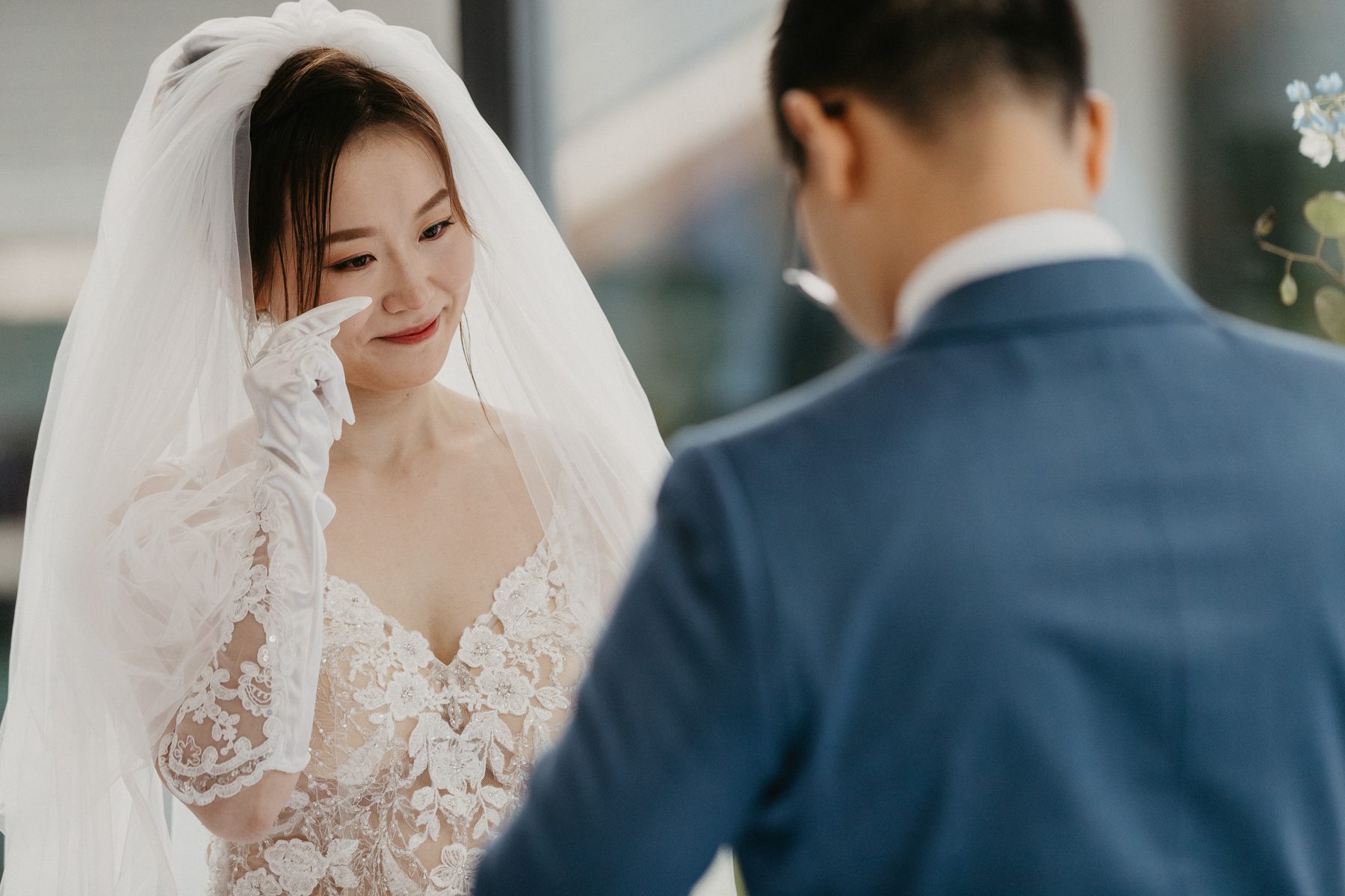 Bride wiping away tears as she listens to her partner speak