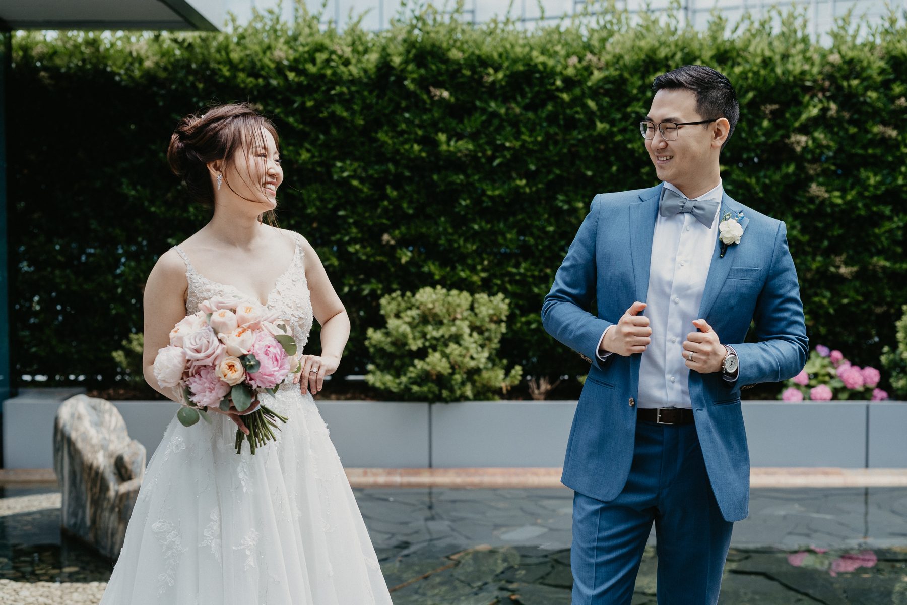 Chelsea and Andrew standing together on a planted rooftop terrace surrounded by green hedges