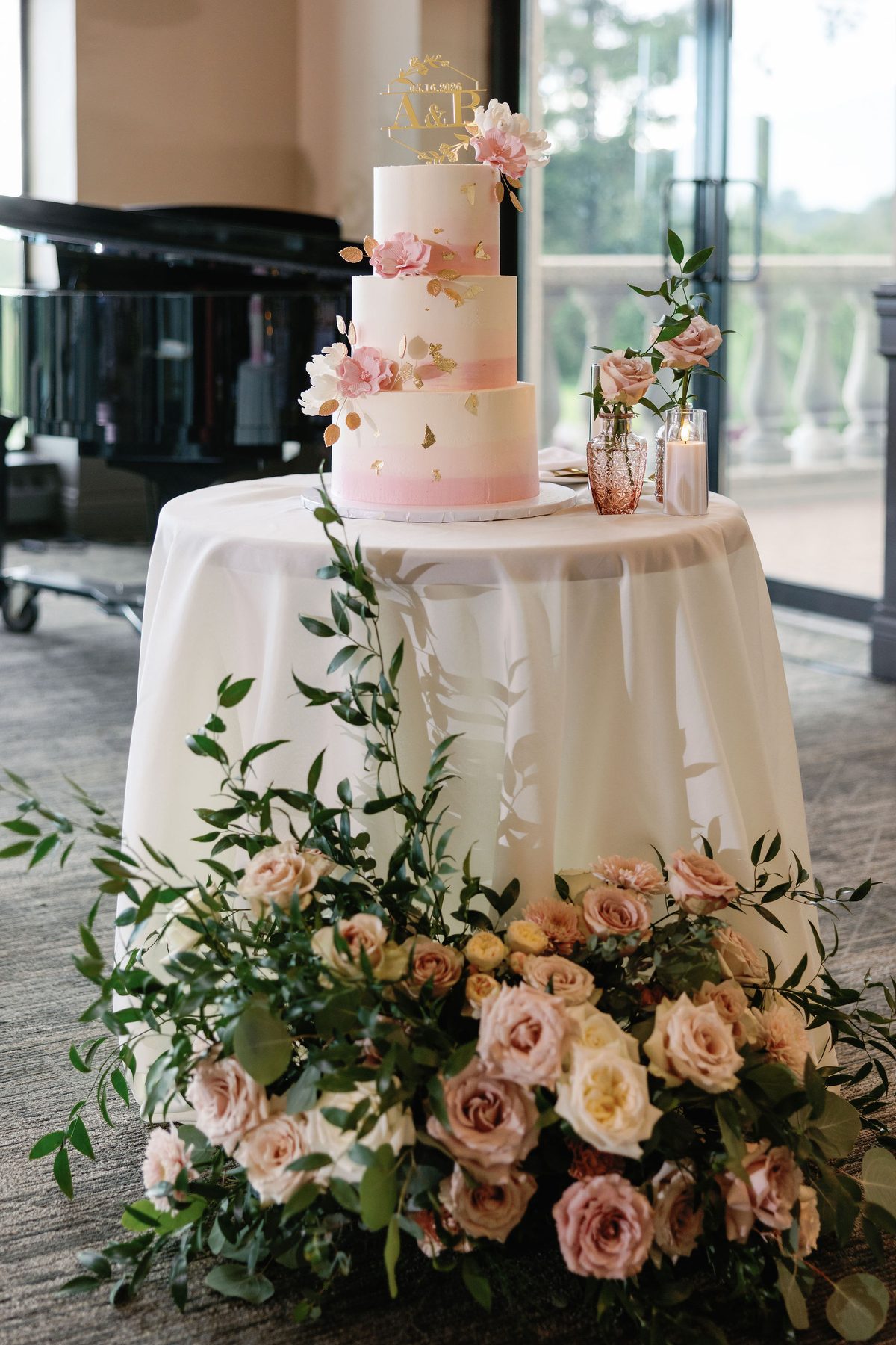 Blush tiered wedding cake surrounded by garden roses