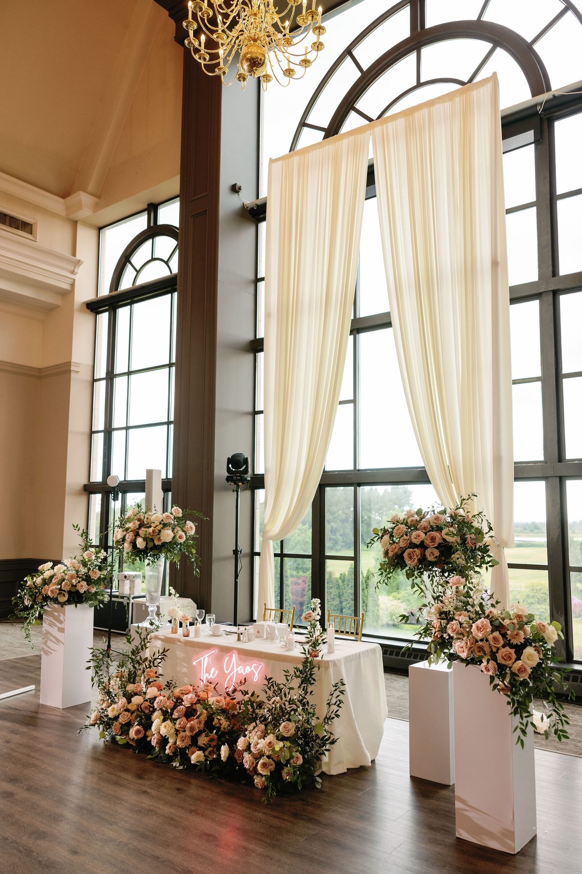 Floral-framed ceremony space with tall windows and soft cream drapery