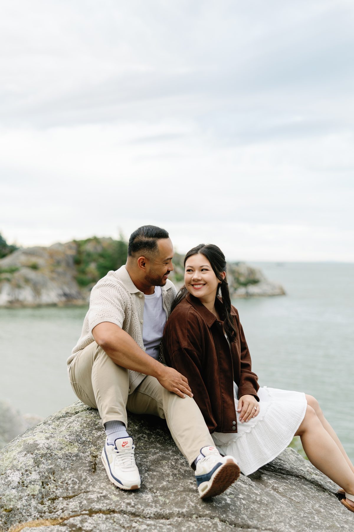 Couple sitting together on a granite shelf above the ocean
